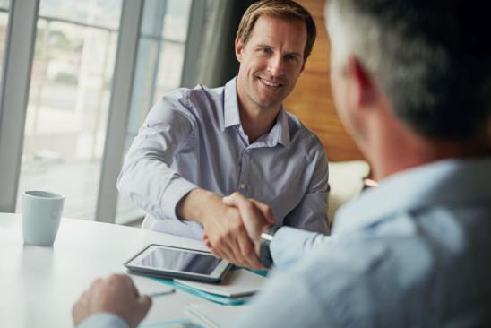 Shot of two businessmen shaking hands while sitting in an office