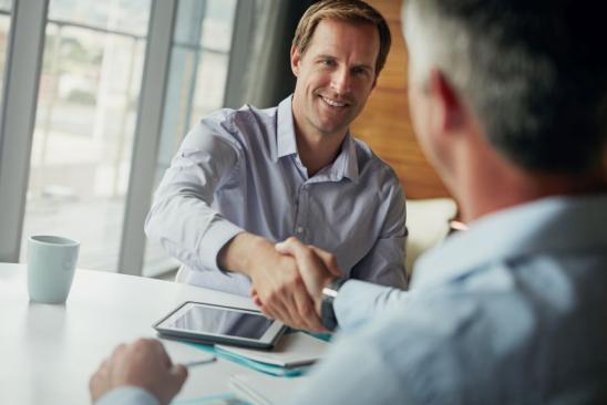 589564456 Shot of two businessmen shaking hands while sitting in an office
