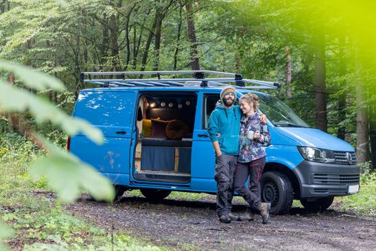 Felix & Miriam stehen im Wald vor ihrem Camper