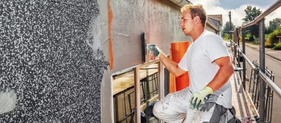 Handwerker auf Gerüst saniert Fassade