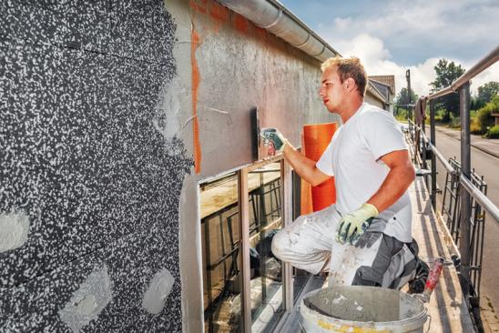 Handwerker auf Gerüst saniert Fassade