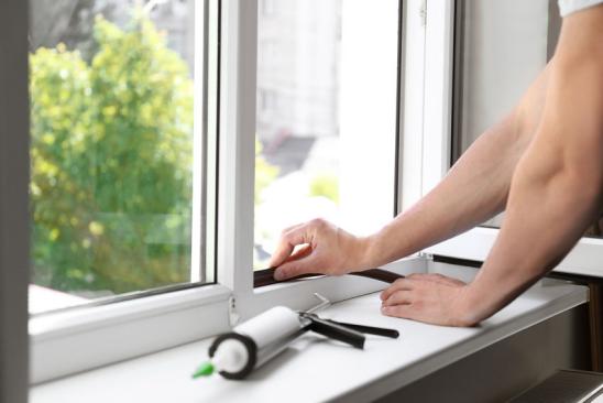 Förderung neue Fenster: Mann bringt neue Dichtung beim Fenstereinbau an