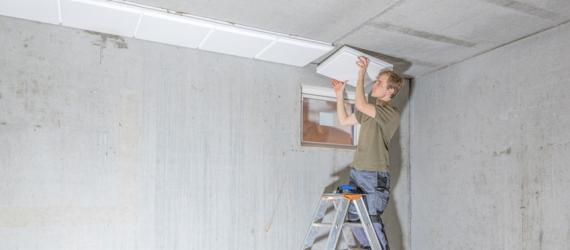 Förderung Kellersanierung: Ein Mann dämmt die Kellerdecke