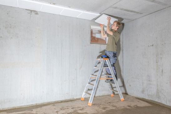 Förderung Kellersanierung: Ein Mann dämmt die Kellerdecke