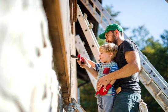 Vater und Sohn streichen Hauswand