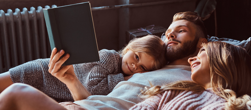 Bausparen mit Wohn-Riester: Vater liest vor, Mutter und Tochter hören zu.