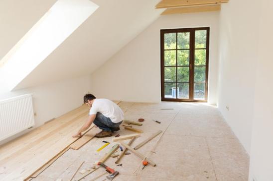 Heimwerker verlegt einen Holzboden im Dachgeschoss