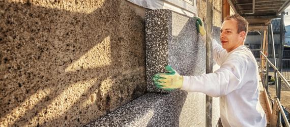 Energetische Sanierung Kosten: Handwerker dämmt Fassade