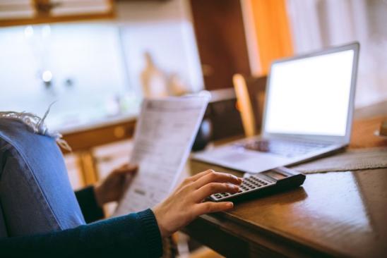 Young female reading her bill papers and using calculator