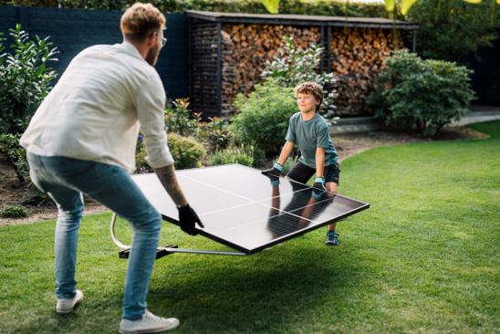 Mann und Sohn tragen das Solarmodul eines Balkonkraftwerkes