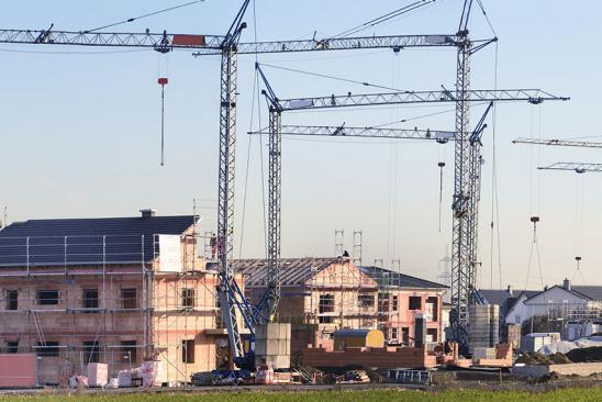 Mehrfamilienhäuser im Rohbau und Kräne davor