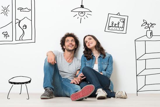 Immobilien Tipps für den Weg zum Eigenheim Junges Paar auf dem Boden sitzend vor Wand mit Skizzen