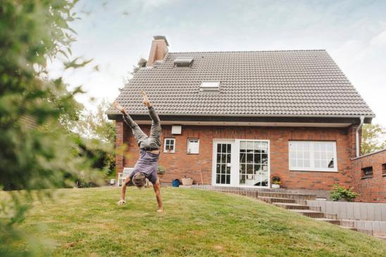 Bestandsimmobilien: Mann macht Handstand vor einem Einfamilienhaus