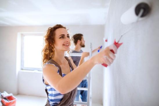 Zwei junge Leute streichen eine Zimmerwand