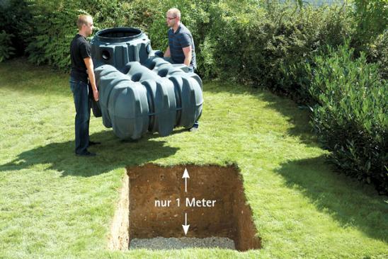 Regenwassertank im Garten - Handwerker, die den Wassertank in das ein Meter tiefe Loch einlassen