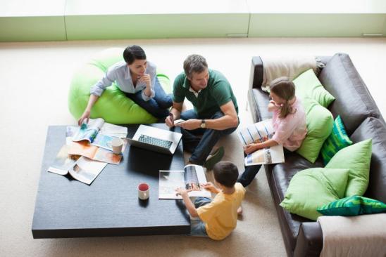 Familie sitzt mit Laptop am Wohnzimmertisch