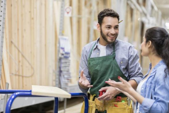 Handsome young male hardware store employee assists female customer with a lumber order.