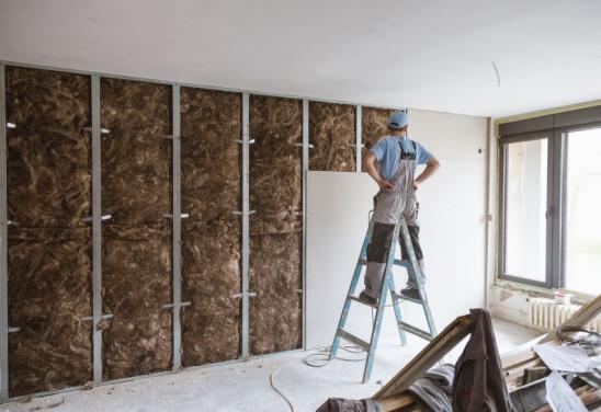 Construction site close up with workers making dry wall and implementing glass wool Earthwool-Acoustic.