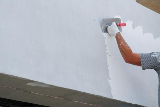 Sanierung Fassade: Mann verputzt Außenwand