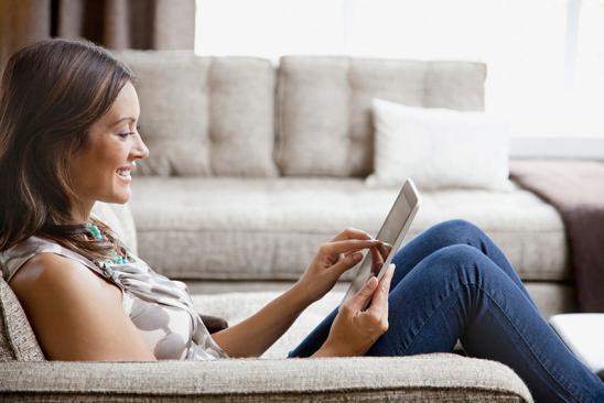 Junge Frau auf Couch mit Tablet